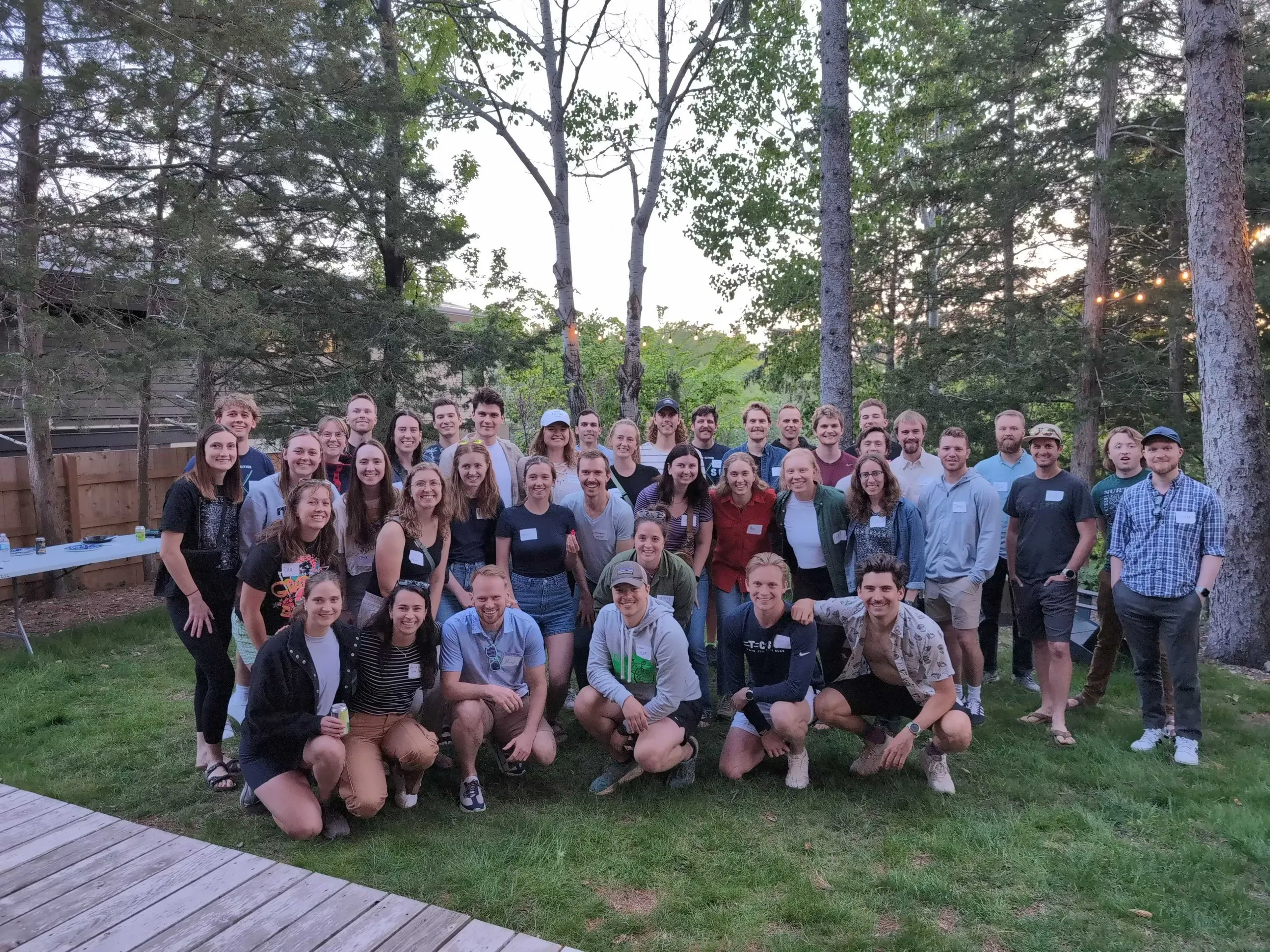 A full group of members posing together at a backyard social, name tags on