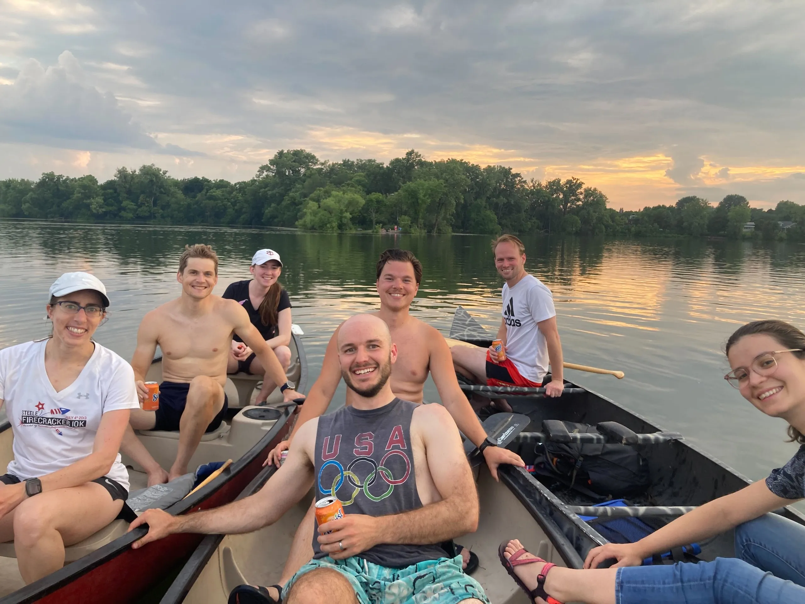 Members in canoes rafted together on a city lake at golden hour