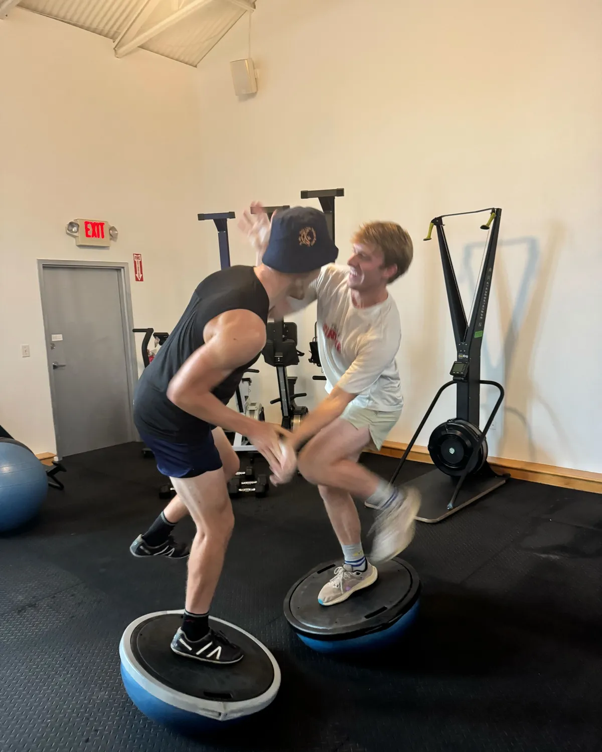 Coach Michael laughing mid-balance on a bosu ball while sparring with a member at a TCSC strength session