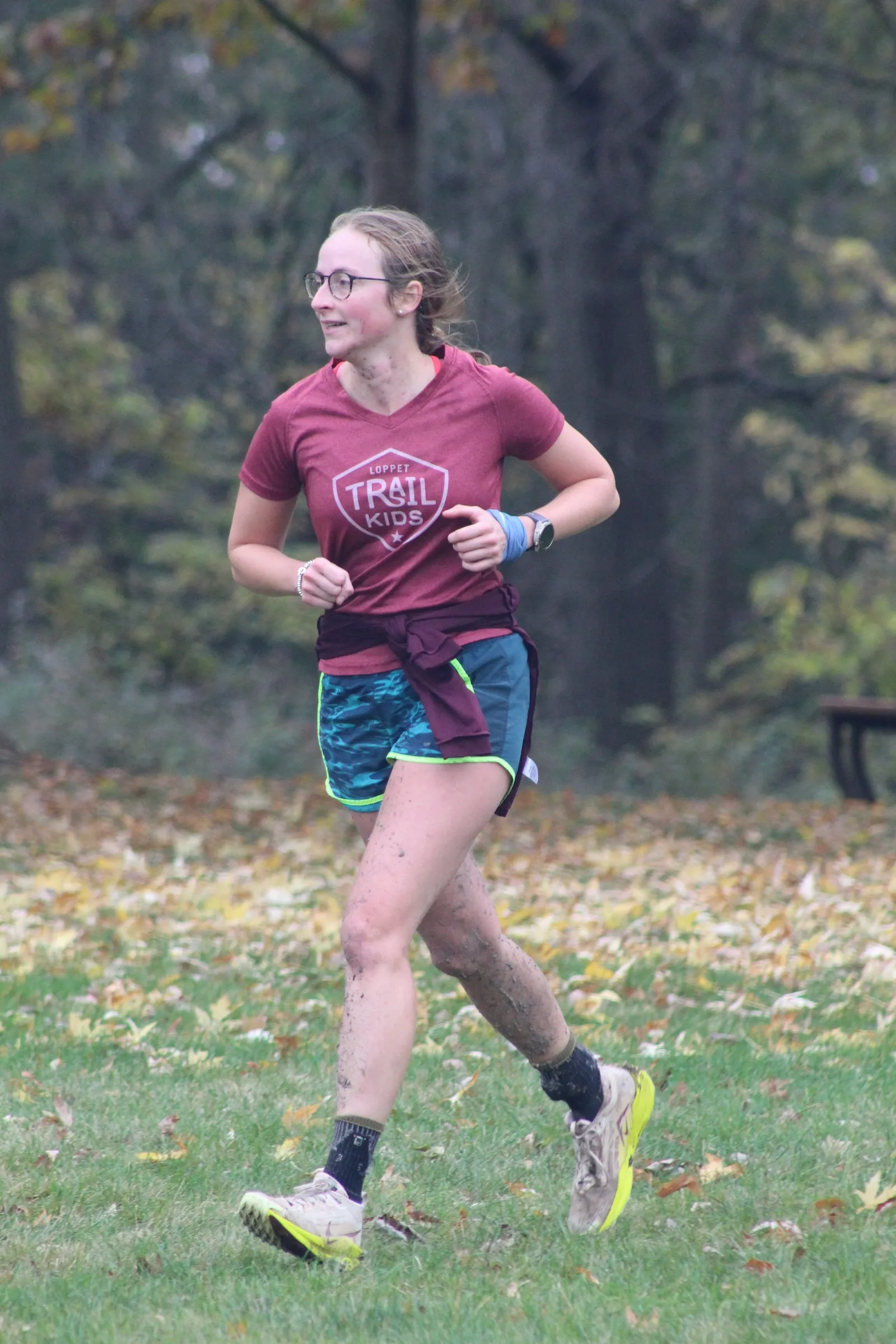 A runner with mud-spattered legs mid-stride on the Dry Tri run leg