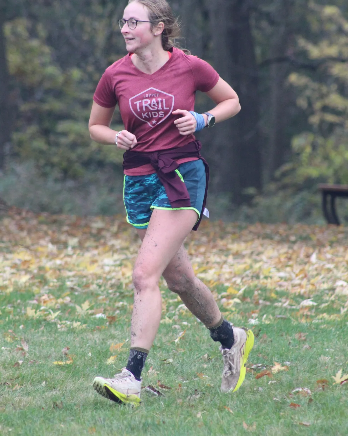 A runner with mud-spattered legs mid-stride on the run leg