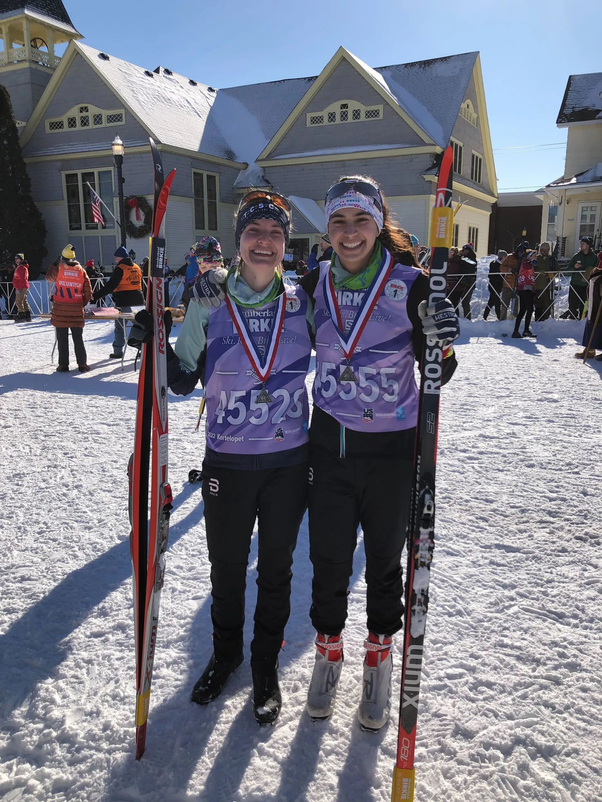 Two finishers with Kortelopet medals and bibs grinning in bright winter sun