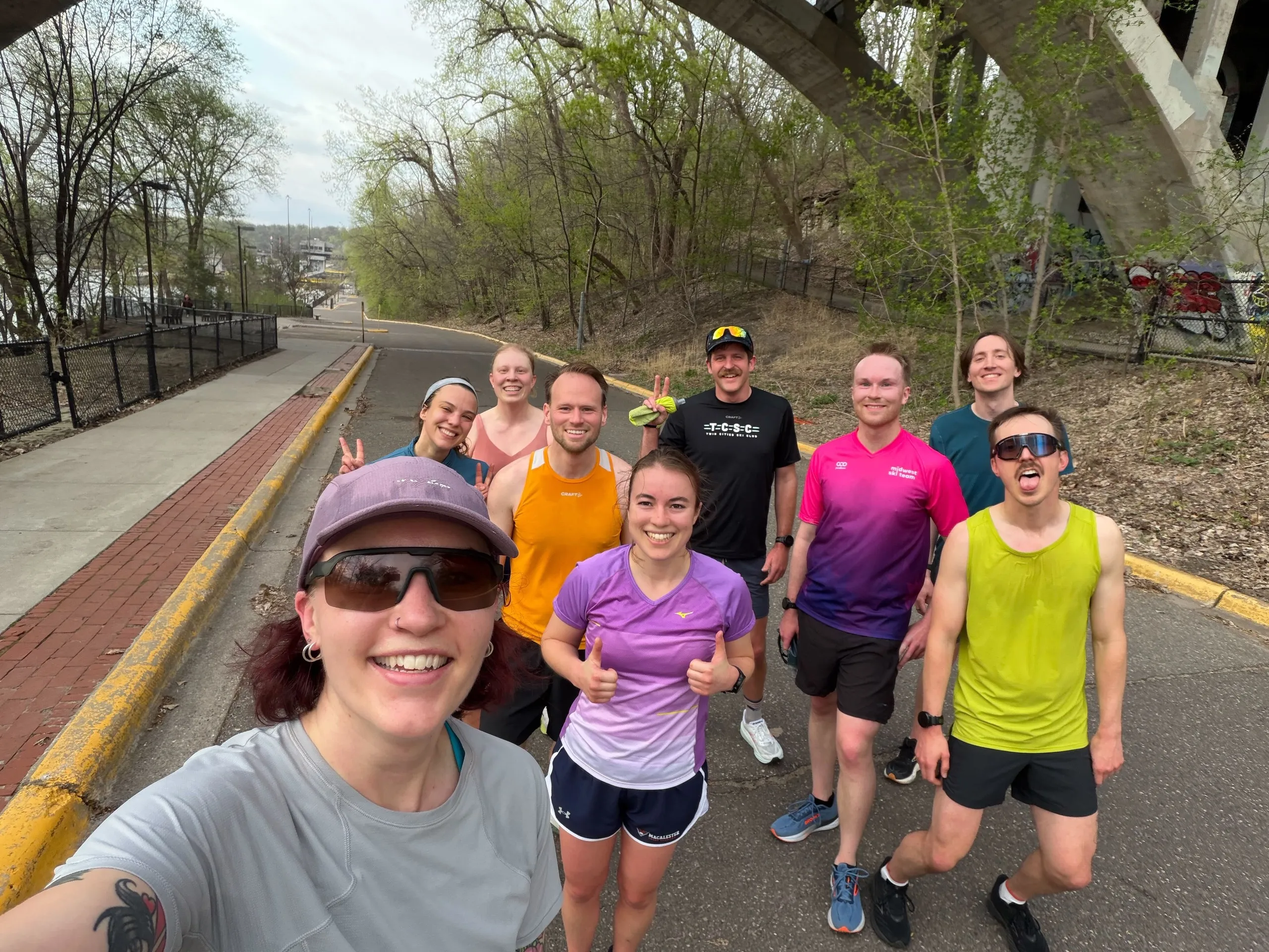 A grinning group selfie mid-run, thumbs up all around