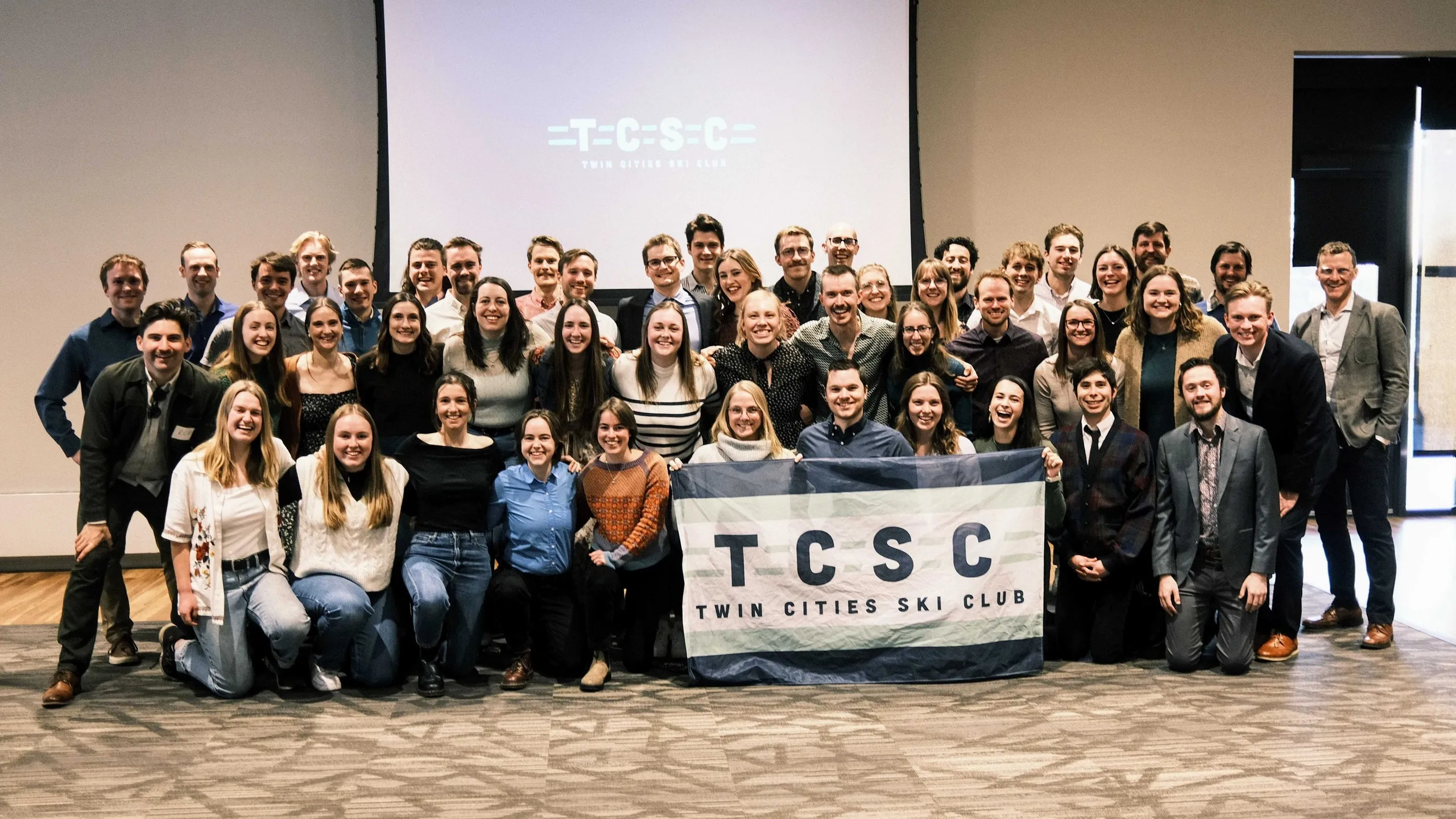 Around fifty TCSC members posing together behind the club banner