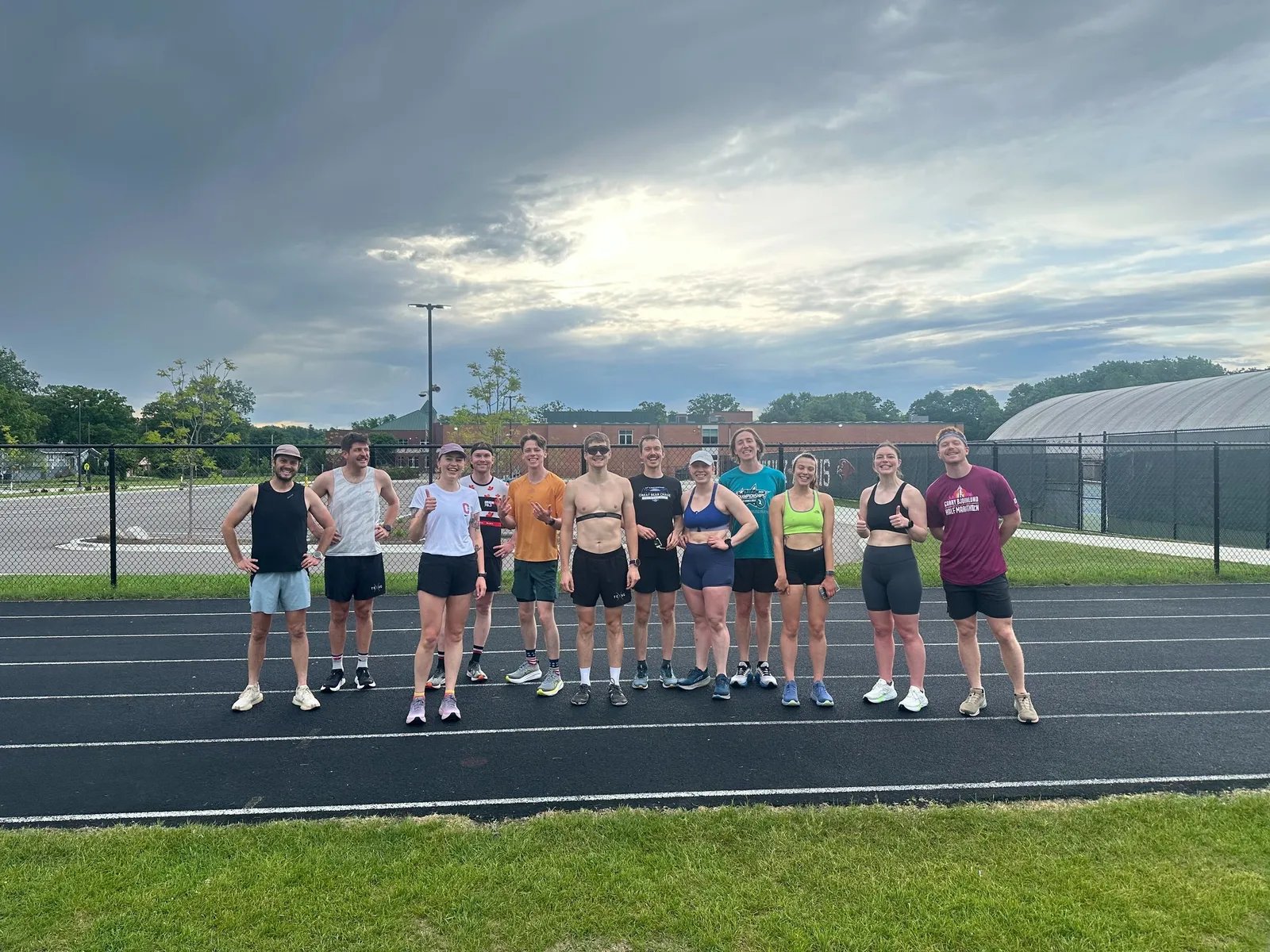 A dozen members on the track under a dramatic storm sky after Thursday Track Club